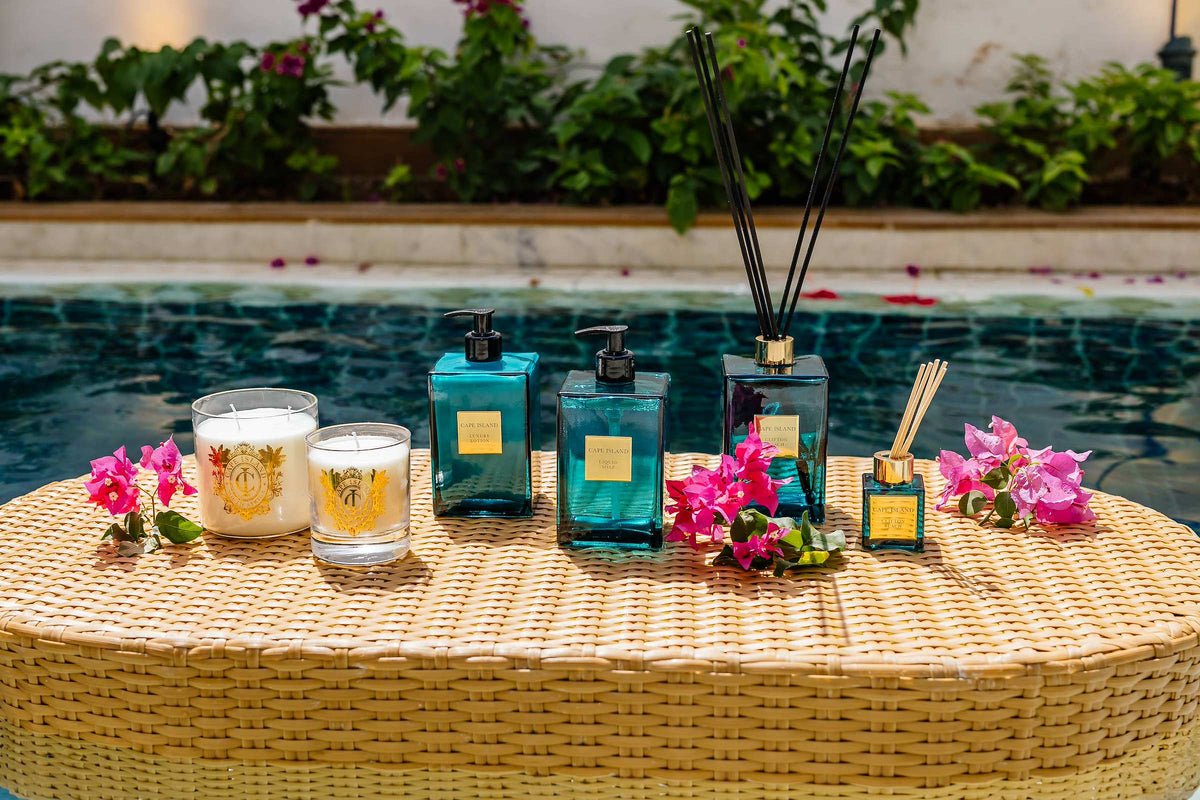 Cape Island candles and diffusers on a rattan tray beside a courtyard pool in Jaipur